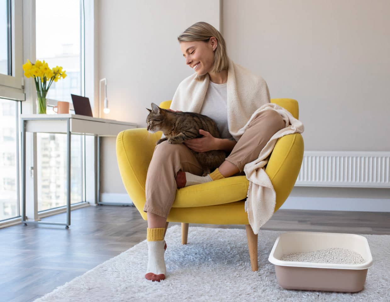 Woman sitting on a yellow chair holding a cat in a modern living room.