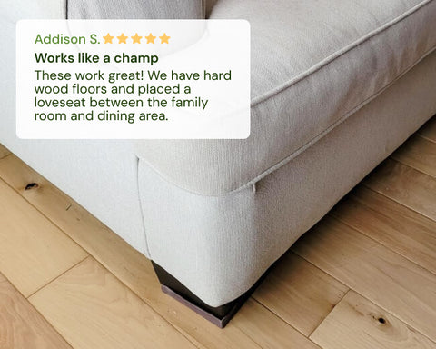 Gray sofa with a CasterMaster non-slip rubber furniture stopper under it on a wooden floor, featuring a customer review.